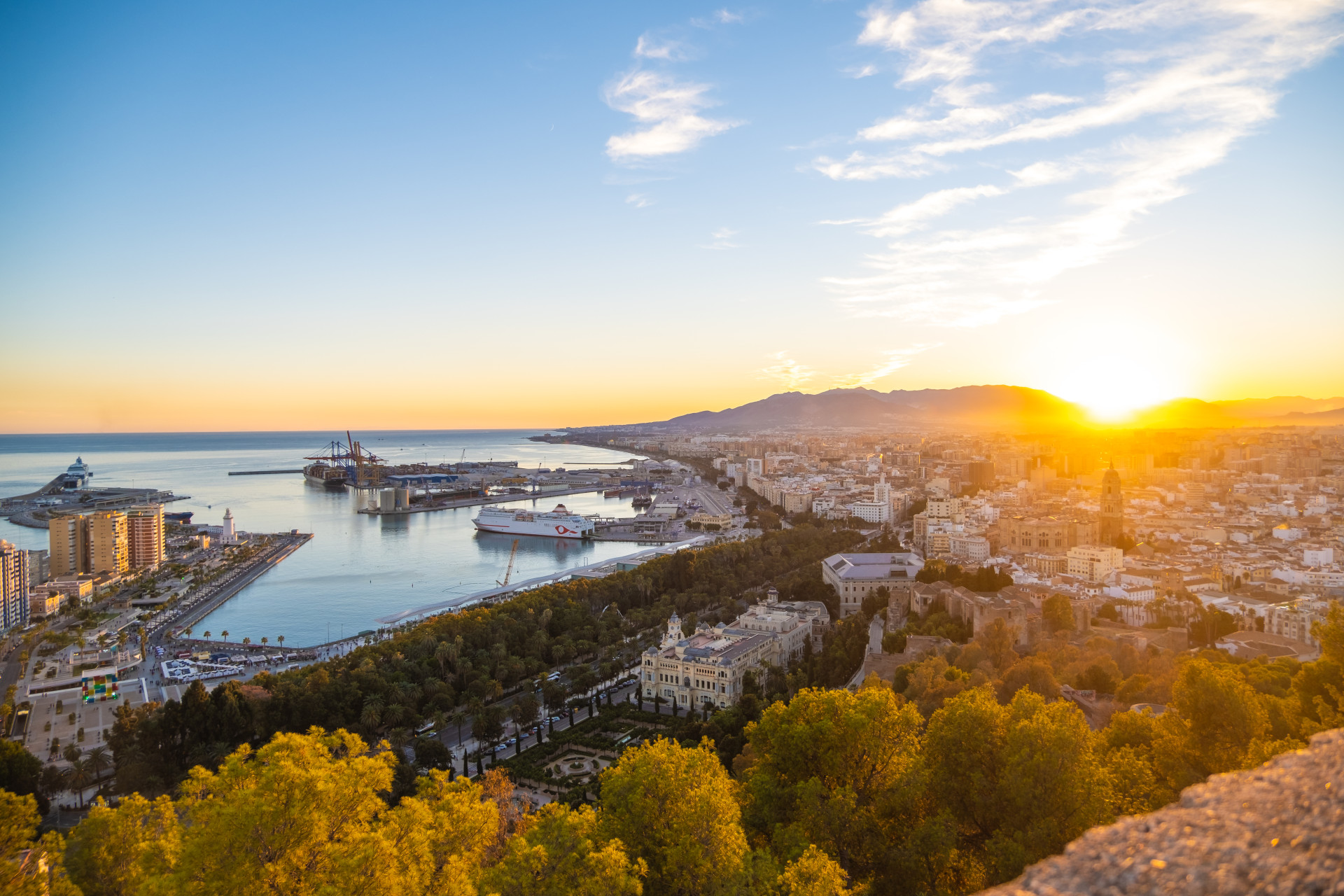 Impuestos al comprar una casa en Málaga: vista de la ciudad y el puerto al atardecer